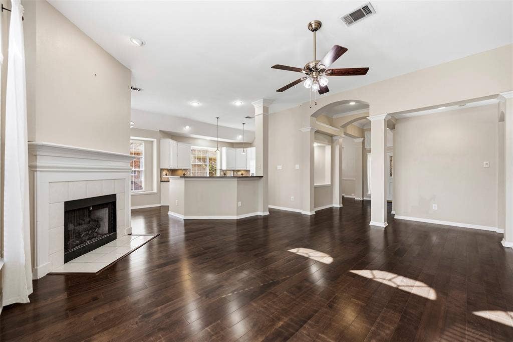 2910 Live Oak Drive, Rowlett, TX 75088 Wood-finish flooring, a white mantel fireplace, and ceiling fan with integrated lighting