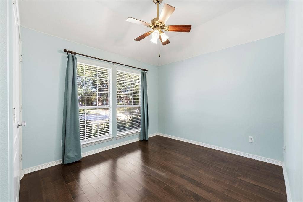 2910 Live Oak Drive, Rowlett, TX 75088 Wood-finish flooring, dual windows with blinds, ceiling fan with integrated lighting, and light blue wall finish