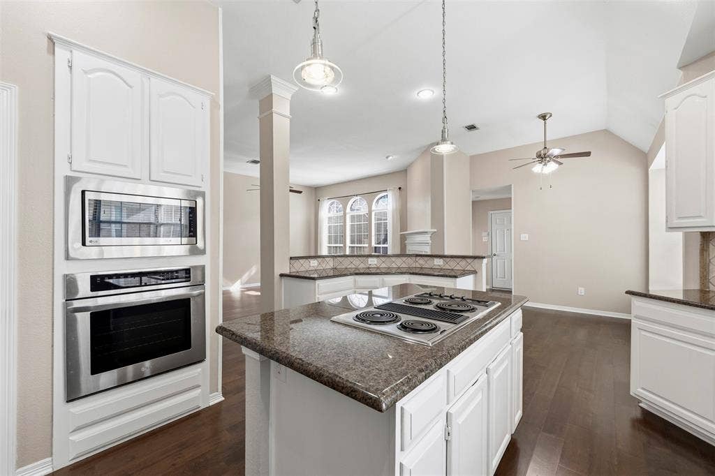2910 Live Oak Drive, Rowlett, TX 75088 Kitchen featuring an island with a built-in cooktop, white cabinetry, granite countertops, and stainless steel built-in appliances