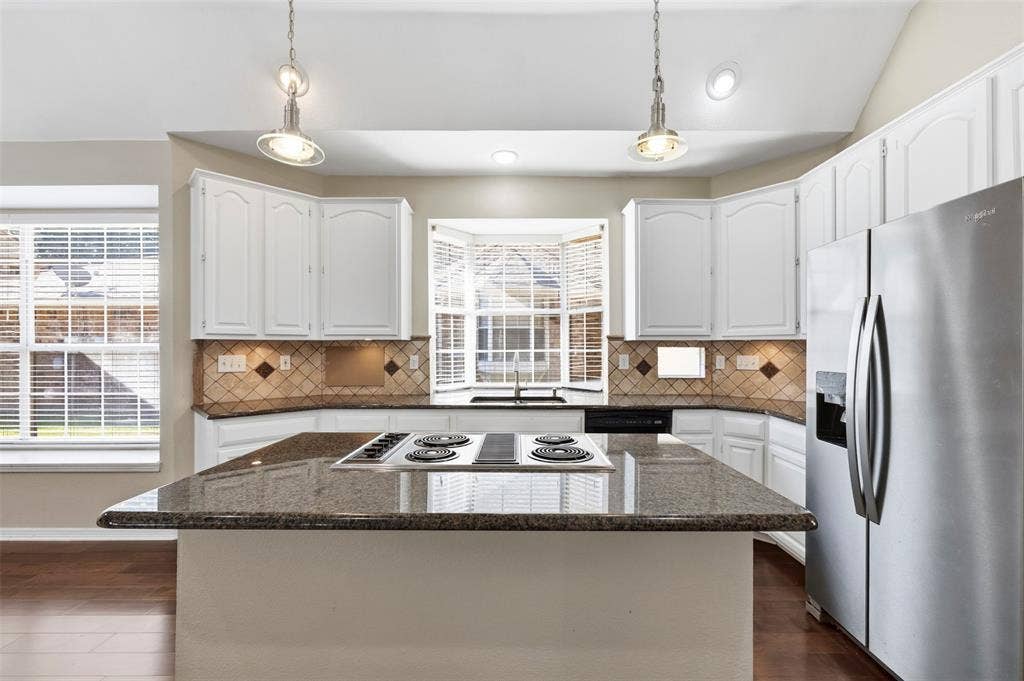 2910 Live Oak Drive, Rowlett, TX 75088 Kitchen featuring a center island cooktop, white cabinetry, stainless steel appliances, a bay window, and pendant lighting