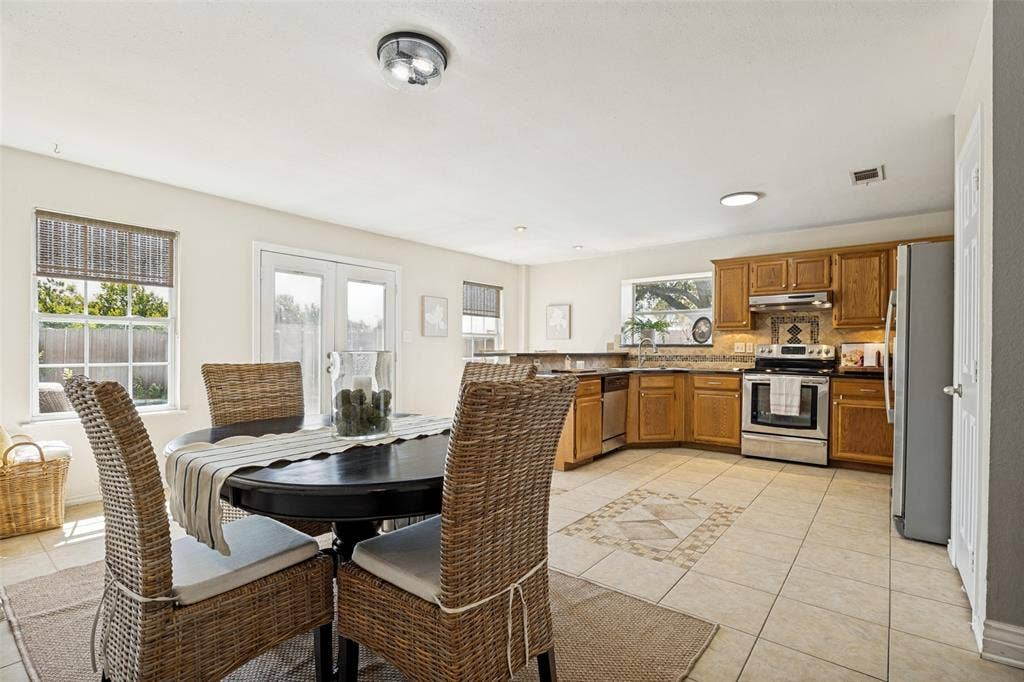 2922 Andrea Lane, Garland, TX 75040 Open-concept kitchen featuring wood cabinetry, stainless steel appliances, and a tile backsplash