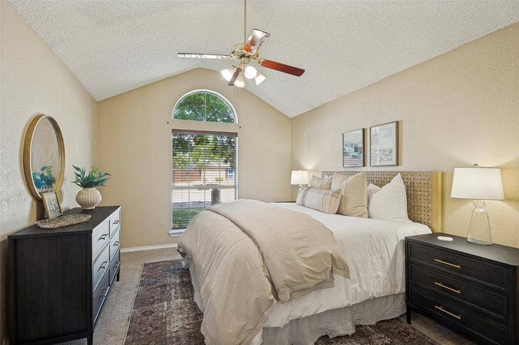 2922 Andrea Lane, Garland, TX 75040 Primary Bedroom: Vaulted ceiling with ceiling fan, arched transom window, and carpeted flooring