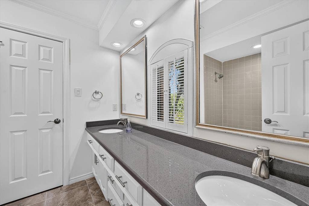 Dual vanity with integrated sinks, dark stone-finish countertop, and white cabinetry