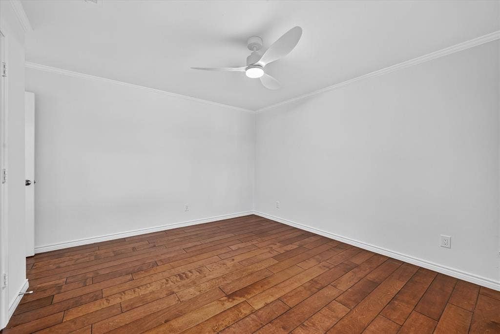 Hardwood flooring, crown molding, white walls, white ceiling fan with integrated lighting, and white trim