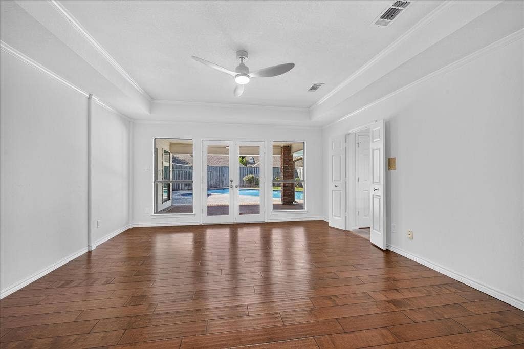 large primary bedroom, open to covered patio, wood-finish flooring  ceiling fan
