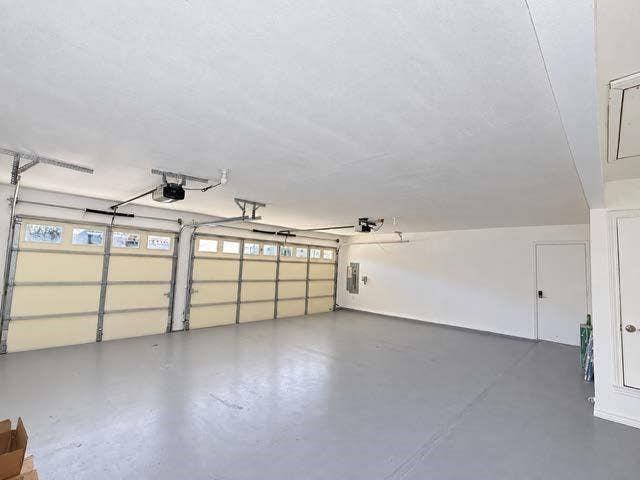 Three-car garage featuring a painted floor and two garage door openers
