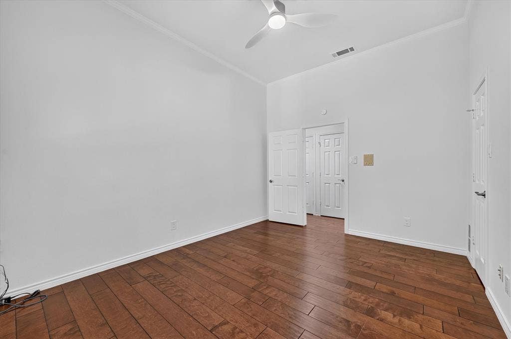 Vaulted ceiling with a ceiling fan, wood-finish flooring, and white interior doors