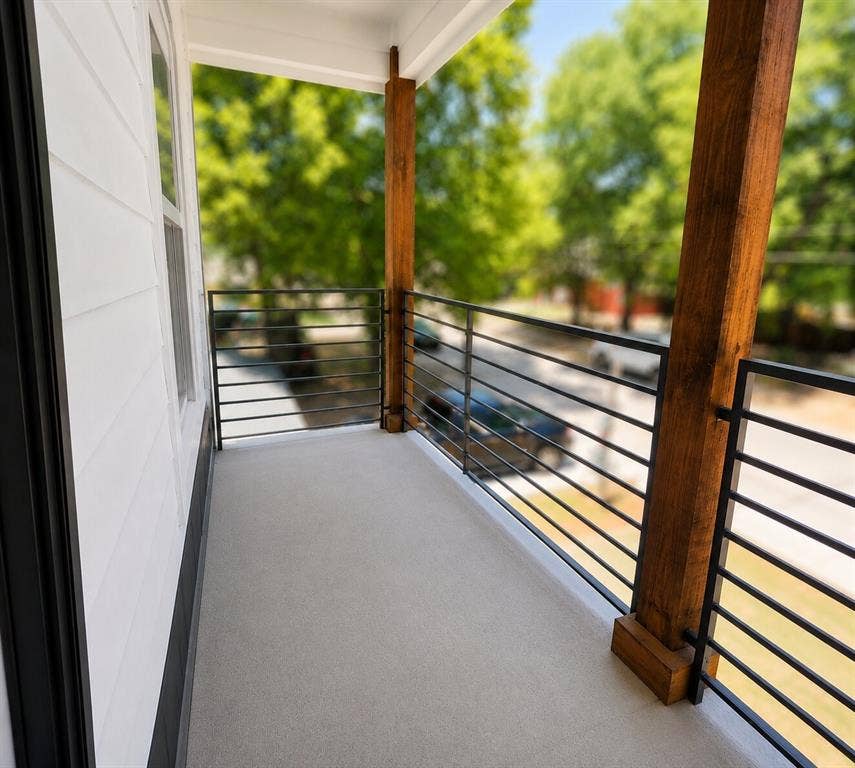 2542 Hooper Street, Dallas, TX 75215 Balcony featuring a concrete surface, black metal railings, and exposed wood support beams