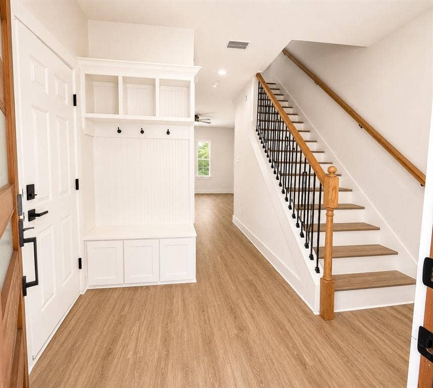 2542 Hooper Street, Dallas, TX 75215 Entryway with wood-finish flooring, built-in mudroom storage, and staircase featuring wood handrails and black metal balusters