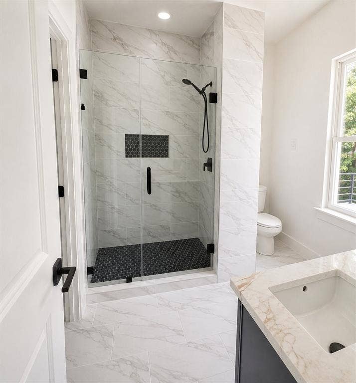 2542 Hooper Street, Dallas, TX 75215 Glass-enclosed shower with black hexagon tile flooring and a recessed shelf