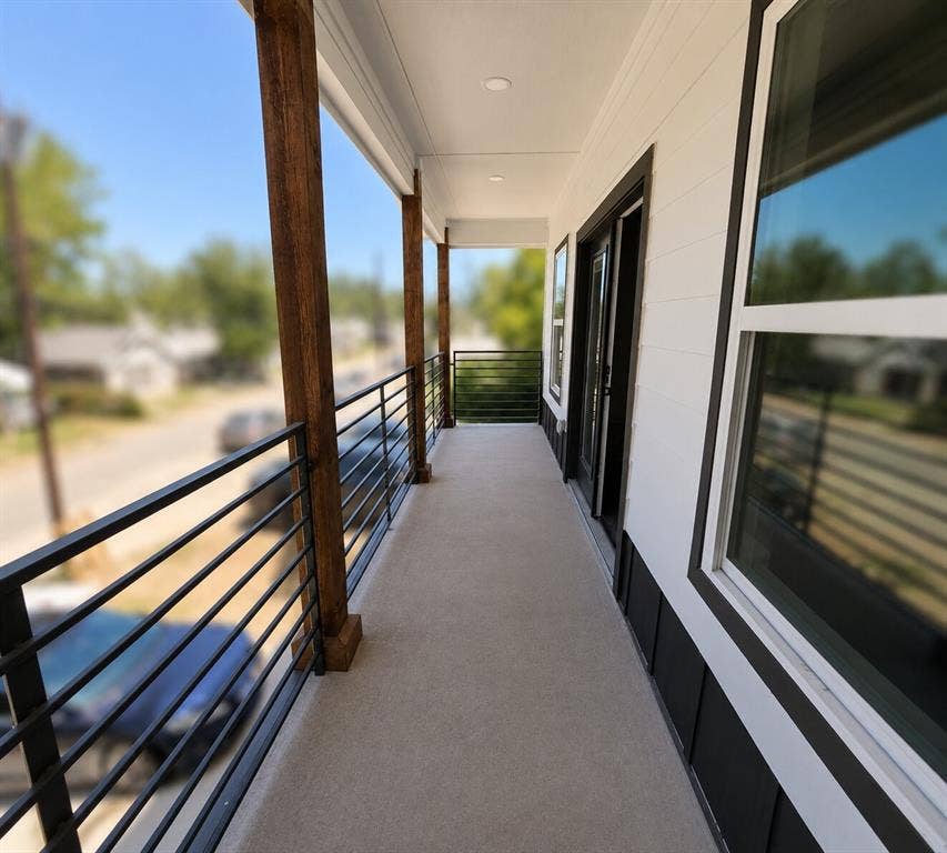 2542 Hooper Street, Dallas, TX 75215 Covered concrete balcony with exposed wood columns, black horizontal metal railings, and recessed lighting