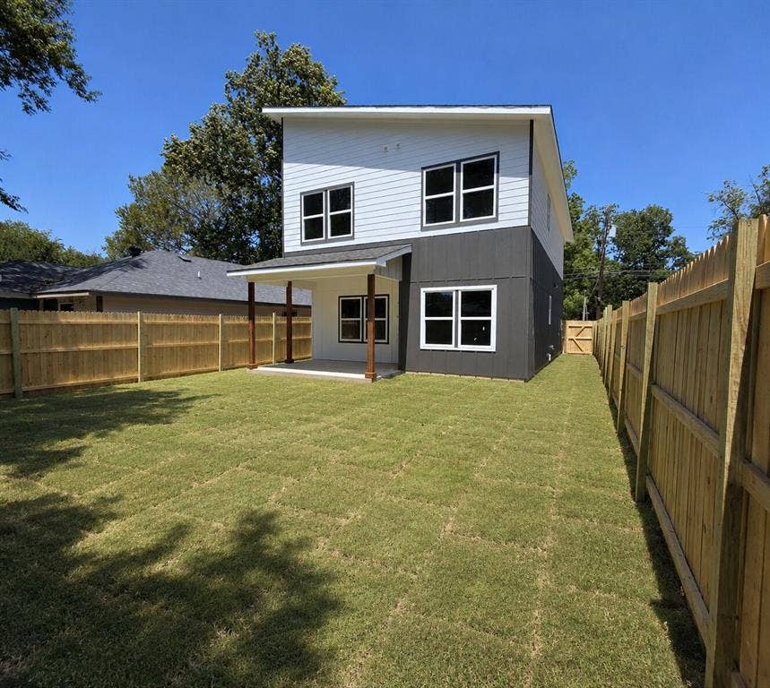 2542 Hooper Street, Dallas, TX 75215 Expansive backyard featuring a manicured lawn, full privacy fencing, and a covered patio with wooden posts