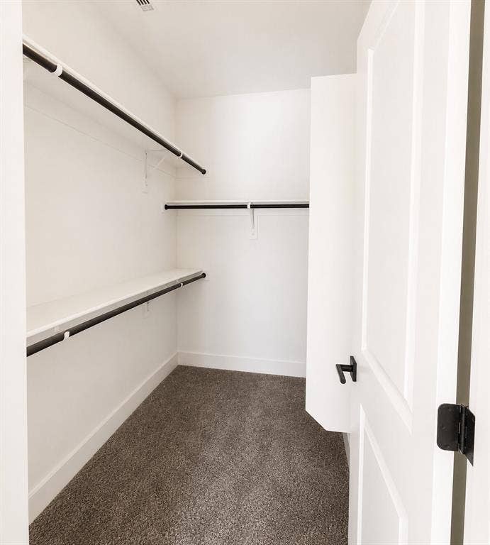 2542 Hooper Street, Dallas, TX 75215 Walk-in closet with white walls, three rows of shelving, black clothing rods, and gray carpet flooring