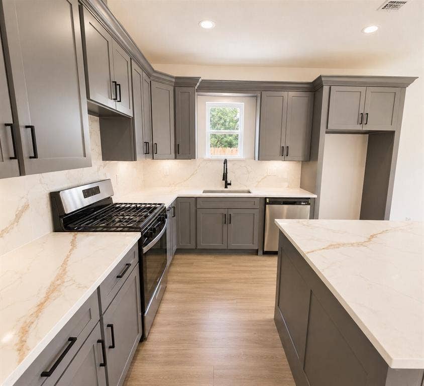 2542 Hooper Street, Dallas, TX 75215 Grey shaker-style cabinetry, wood-finish flooring, stainless steel appliances, white countertops with veining, and a black faucet