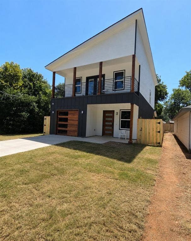2542 Hooper Street, Dallas, TX 75215 Contemporary two-story exterior with a striking roofline, featuring a wood-finish garage door, a second-story balcony with metal railings, and a concrete driveway