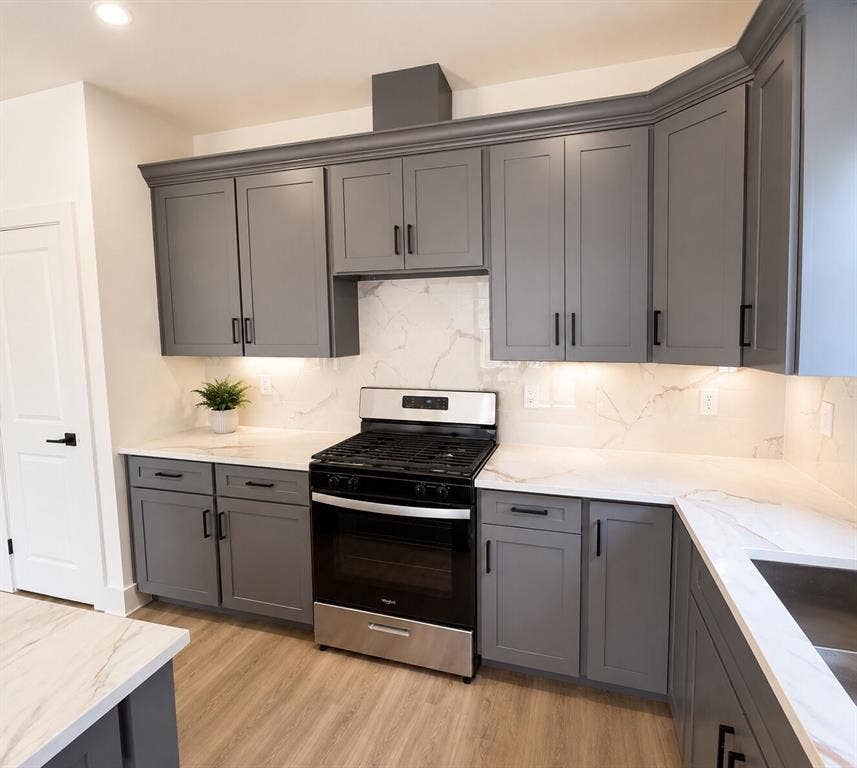 2542 Hooper Street, Dallas, TX 75215 Gray shaker-style cabinetry with crown molding, stainless steel range, white countertops with veining, and wood-finish flooring