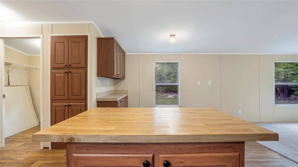 5390 Fm 314 S, Larue, TX 75770 Kitchen island with a light wood-finish countertop, wood cabinetry with black hardware, and wood-finish flooring
