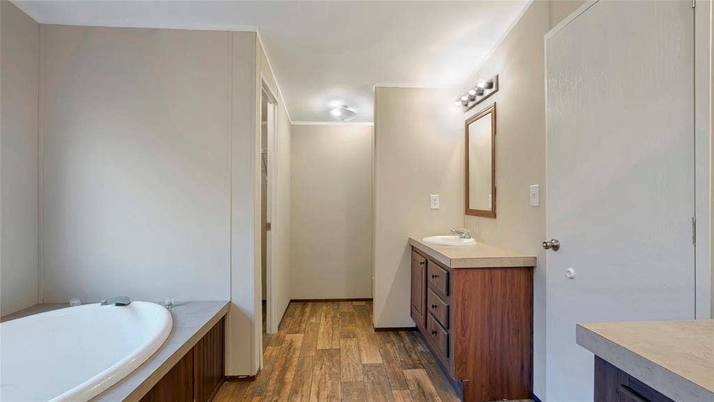 5390 Fm 314 S, Larue, TX 75770 Soaking tub with integrated faucet, wood-finish flooring, vanity with integrated sink, wood-finish cabinetry, and overhead lighting