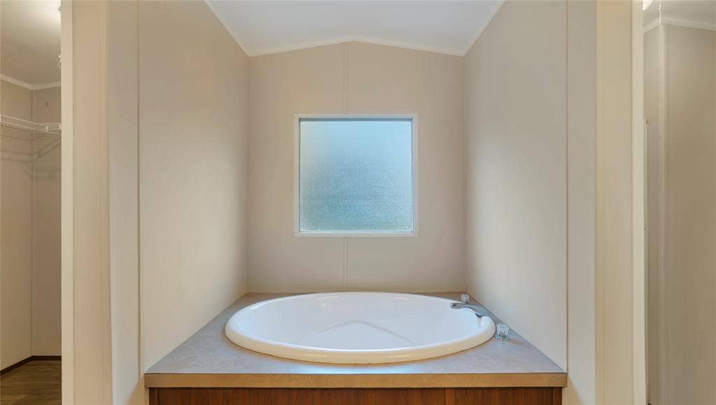 5390 Fm 314 S, Larue, TX 75770 Soaking tub with a built-in surround, wood-finish cabinetry, and a frosted window