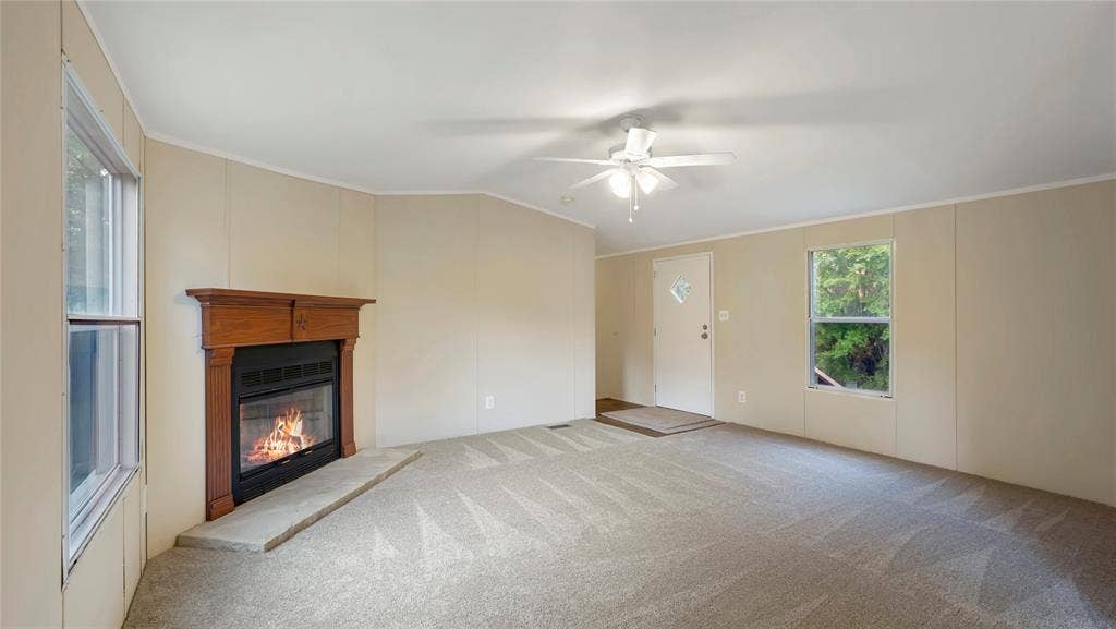 5390 Fm 314 S, Larue, TX 75770 Living area featuring a fireplace with a wood-finish mantel, neutral carpet, ceiling fan, and two windows