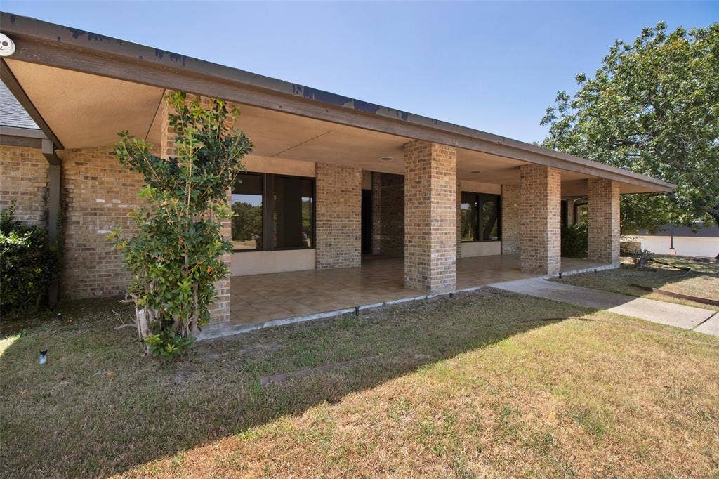 3210 W Northwest Loop 323, Tyler, TX 75702 Brick exterior with an expansive covered patio, featuring multiple support columns, large windows, and a paved walkway