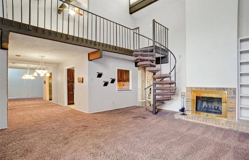 12502 Burninglog Lane, Dallas, TX 75243 Spiral staircase, brick fireplace with brass surround, built-in shelving, loft area, and vaulted ceilings