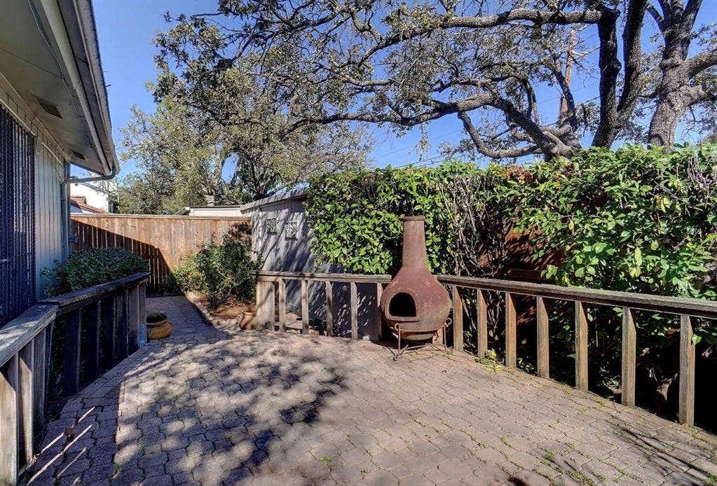 12502 Burninglog Lane, Dallas, TX 75243 Paved patio surface, wood railing, privacy fencing, mature trees, and landscaping