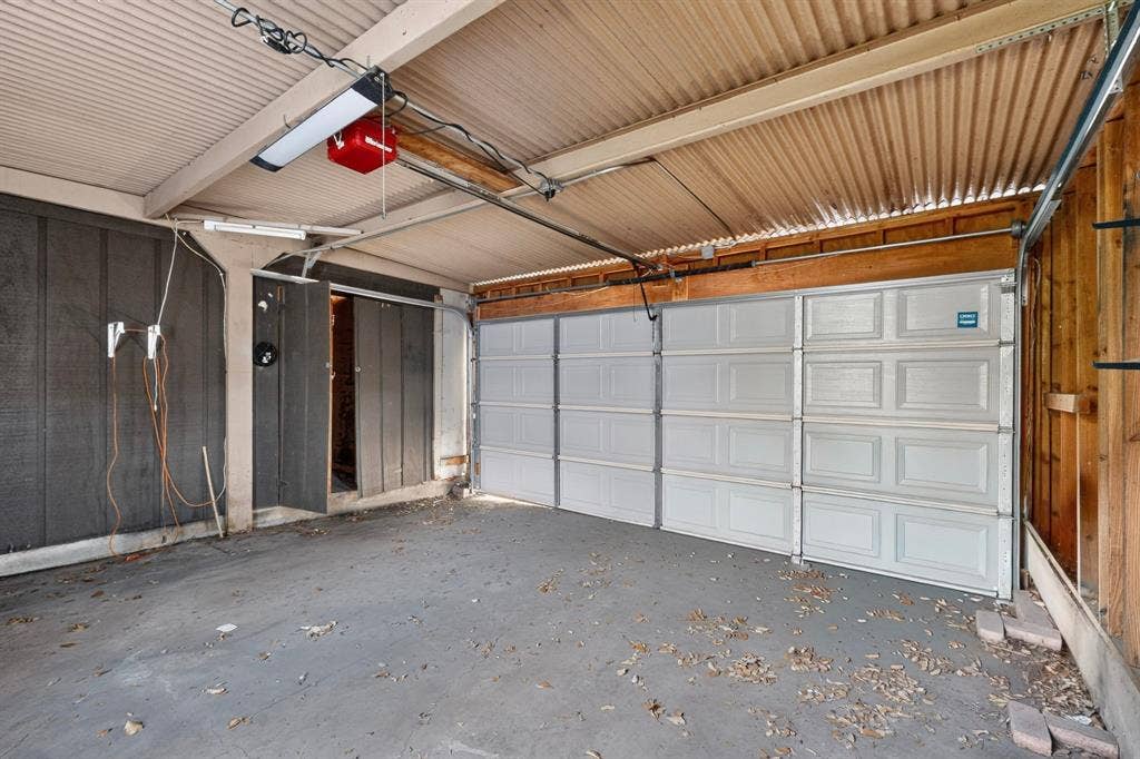12502 Burninglog Lane, Dallas, TX 75243 Enclosed garage space with a paneled garage door and corrugated ceiling