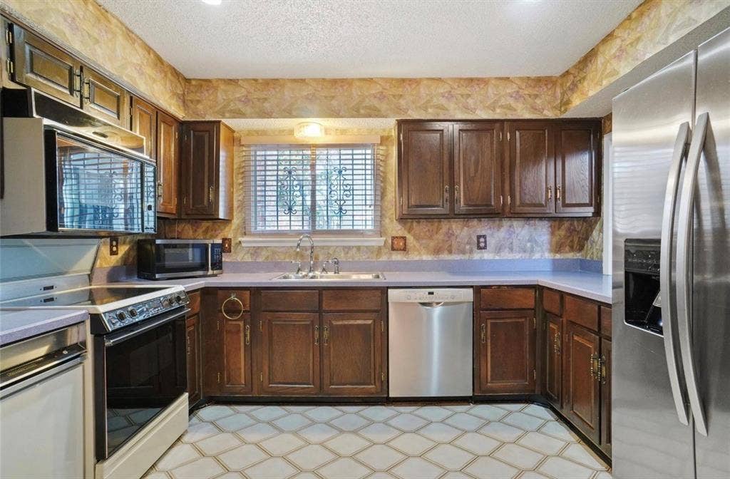 12502 Burninglog Lane, Dallas, TX 75243 Kitchen featuring wood cabinetry, stainless steel appliances, and patterned floor