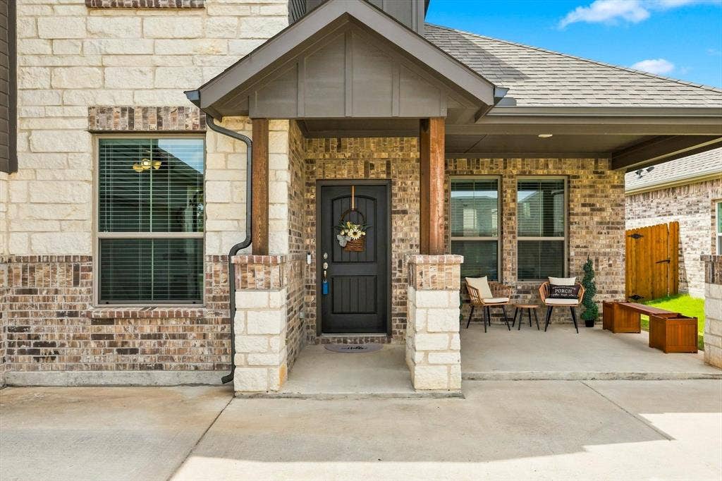 401 Llano Lane, Red Oak, TX 75154 Brick and stone exterior with covered front porch, dark paneled entry door, and composition shingle roof