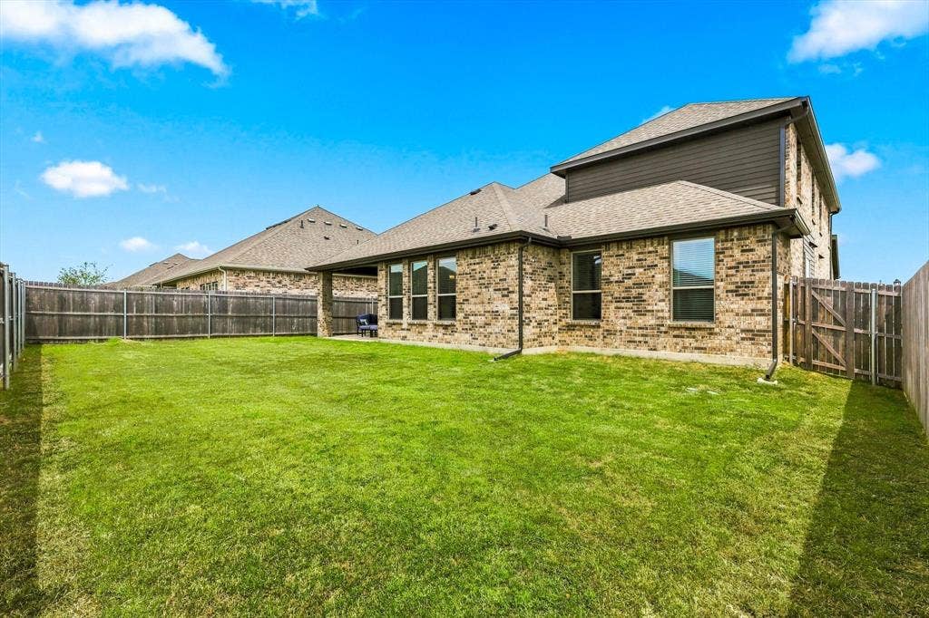401 Llano Lane, Red Oak, TX 75154 Expansive grassy yard with full privacy fencing, brick exterior, and a covered patio area