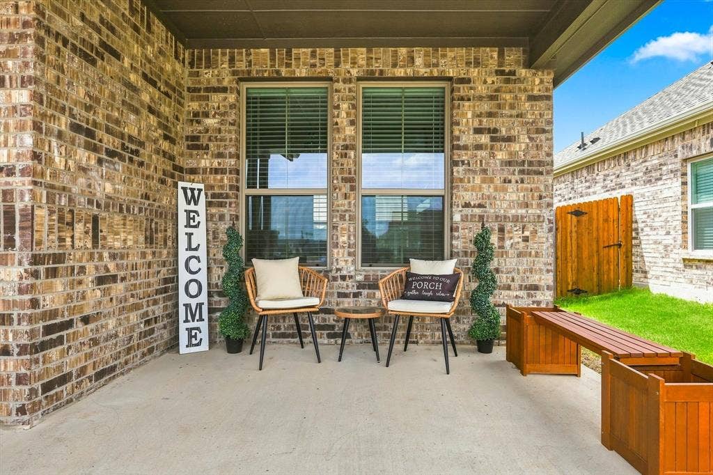 401 Llano Lane, Red Oak, TX 75154 Covered concrete patio featuring brick exterior, dual pane windows, and a wooden privacy fence