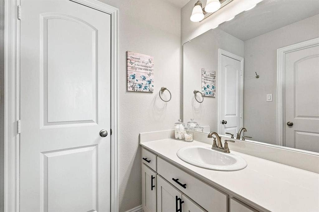 401 Llano Lane, Red Oak, TX 75154 Vanity with a white countertop and integrated sink, brushed nickel faucet, and a large wall-mounted mirror