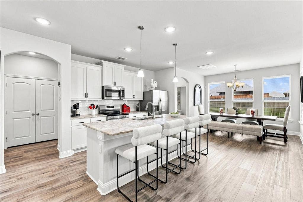 401 Llano Lane, Red Oak, TX 75154 Open-concept kitchen with a large central island, white cabinetry, a subway tile backsplash, and stainless steel appliances