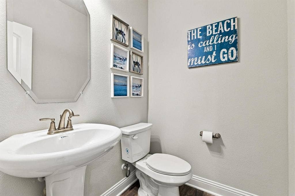 401 Llano Lane, Red Oak, TX 75154 Pedestal sink with a brushed nickel faucet, octagonal mirror, and white toilet