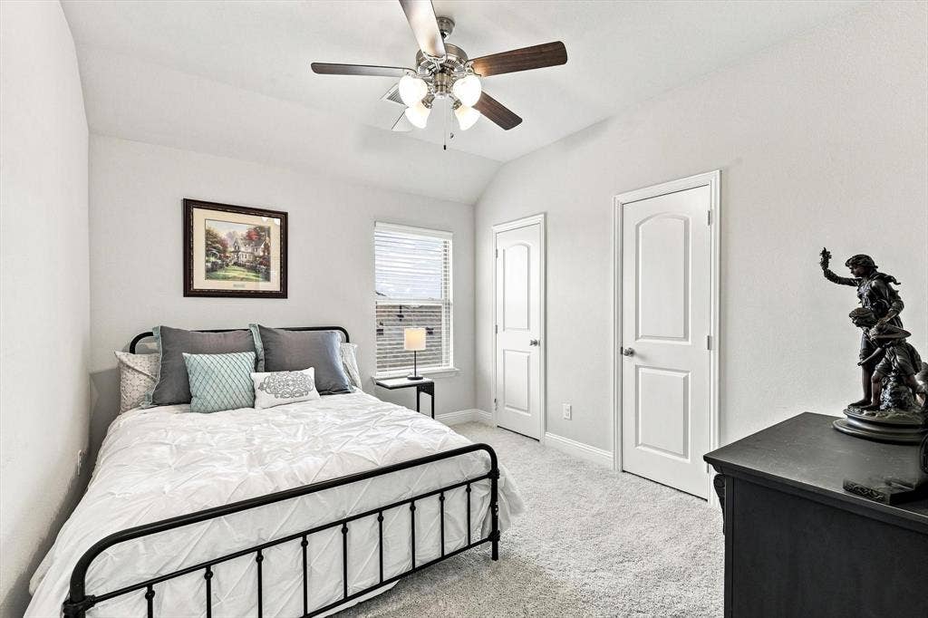 401 Llano Lane, Red Oak, TX 75154 Vaulted ceiling, two paneled doors, window with blinds, ceiling fan with light fixture, and carpeted flooring