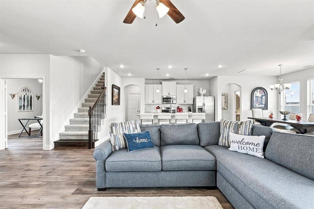 401 Llano Lane, Red Oak, TX 75154 Open-concept living area featuring wood-finish flooring, recessed lighting, and a prominent staircase with dark wood newel posts and iron balusters