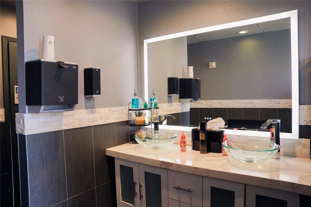 2705 Virginia Parkway, #SLE, McKinney, TX 75071 Vanity with dual glass vessel sinks, stone-finish countertop, and integrated lighted mirror