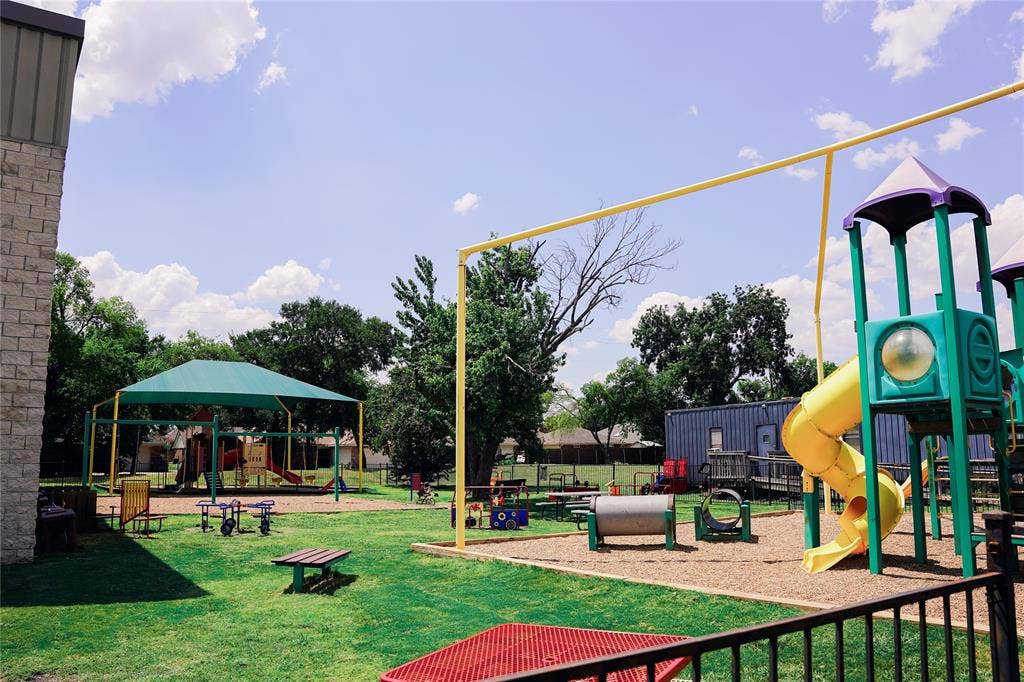 2705 Virginia Parkway, #SLE, McKinney, TX 75071 Expansive outdoor recreation area with natural grass, a large play structure featuring a spiral slide, a shaded play area, and additional playground equipment