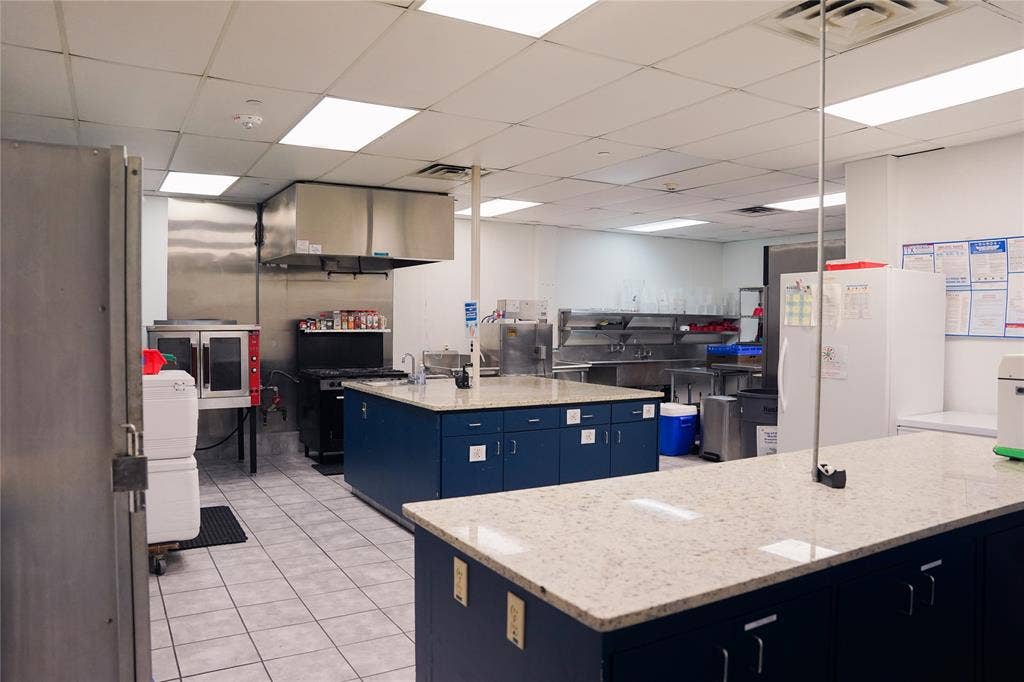 2705 Virginia Parkway, #SLE, McKinney, TX 75071 Commercial kitchen featuring two large islands with speckled countertops, stainless steel appliances, and tiled flooring