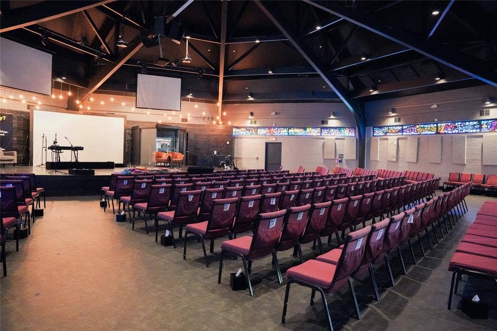 2705 Virginia Parkway, #SLE, McKinney, TX 75071 Spacious interior with an elevated stage, multiple projection screens, exposed ceiling beams, and decorative stained-glass window panels