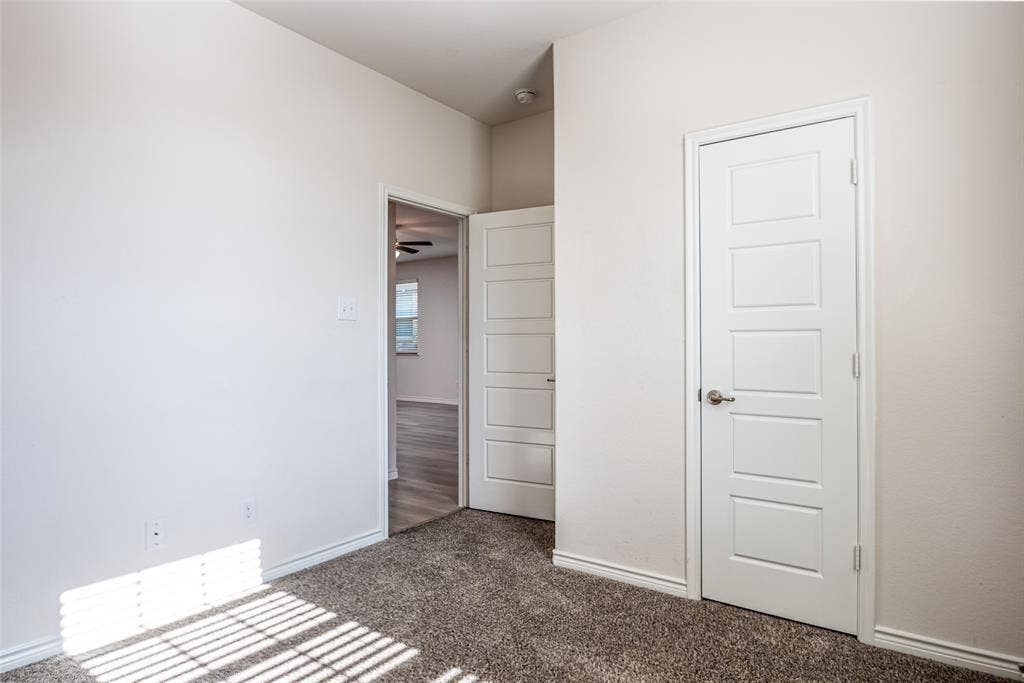 2721 Franklin Drive, Celina, TX 75009 Textured carpeting, white interior doors with contemporary paneling, brushed nickel hardware, light-toned wall finishes, and a ceiling fan in the adjacent space