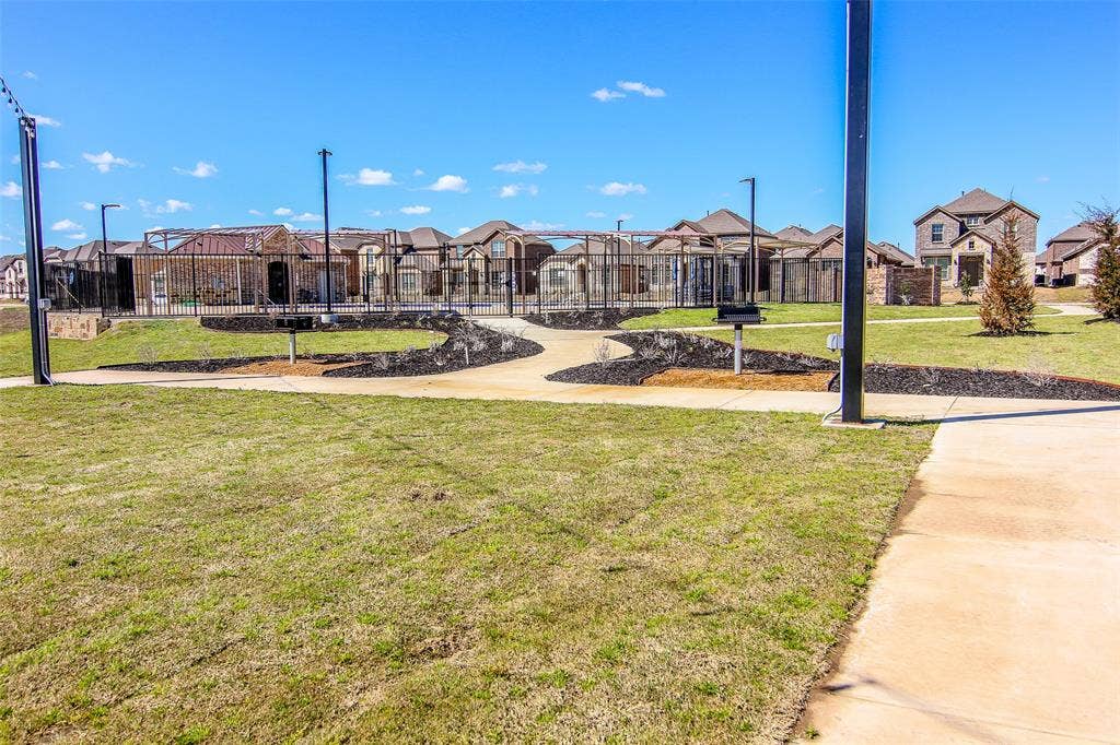 2721 Franklin Drive, Celina, TX 75009 Community green space featuring a paved walkway, established landscaping, and a fenced recreation area with built-in grills