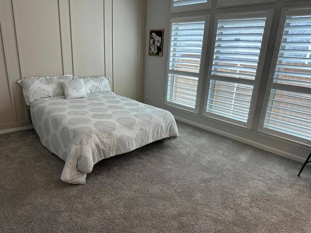 5308 Tupper Avenue, Fate, TX 75087 Wall-to-wall carpeting with vertical wall paneling, featuring a series of tall windows with plantation shutters