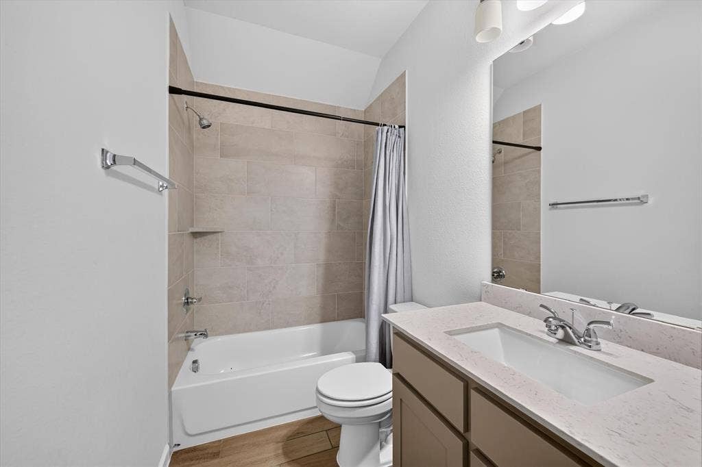 5308 Tupper Avenue, Fate, TX 75087 Bathroom featuring a built-in tub with tile surround, wood-finish flooring, a vanity with an integrated sink, a large mirror, and overhead lighting