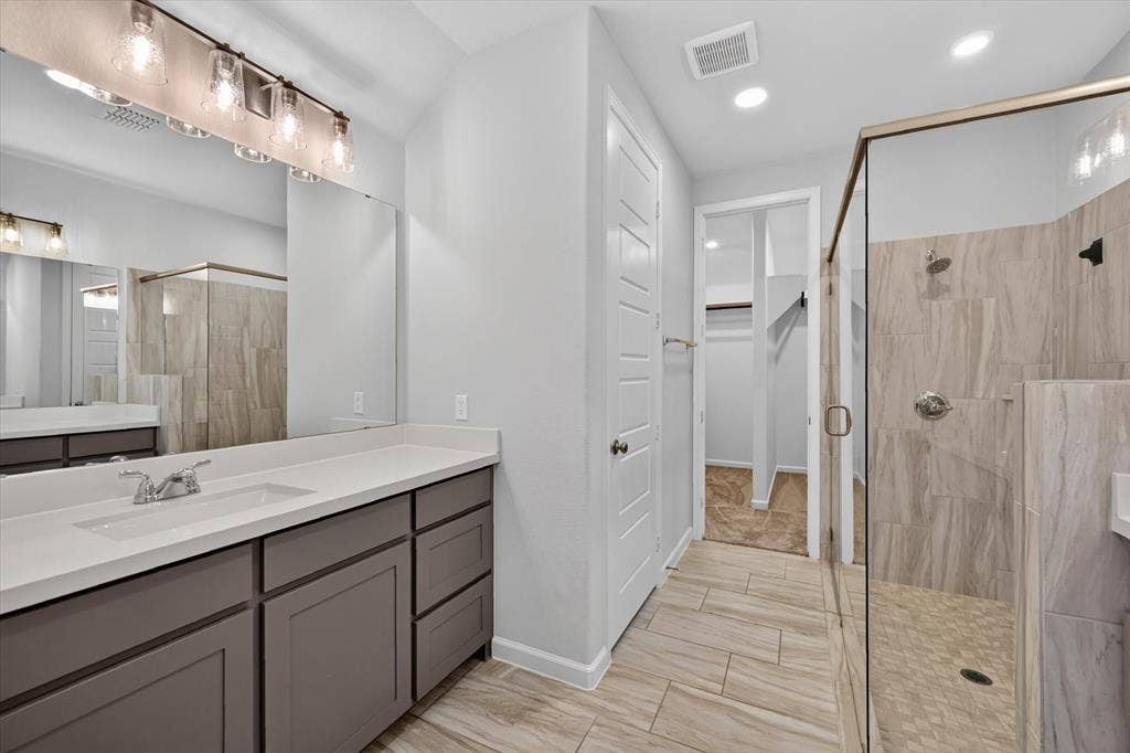 5308 Tupper Avenue, Fate, TX 75087 Spa-inspired primary bathroom featuring a dual-sink vanity with wood cabinetry, white quartz countertops, and polished nickel fixtures
