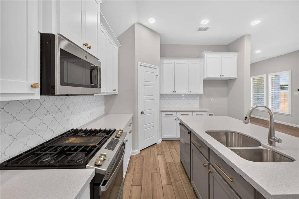 5308 Tupper Avenue, Fate, TX 75087 Kitchen featuring white shaker cabinetry, stainless steel appliances, light-toned countertops, and wood-finish flooring