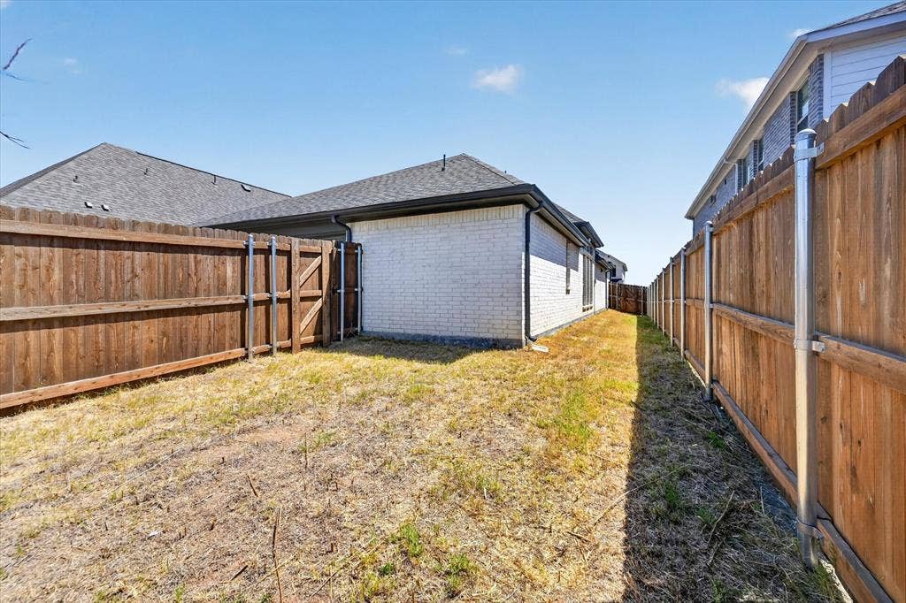 5308 Tupper Avenue, Fate, TX 75087 Enclosed backyard featuring wood fencing, a secure gate, and a white brick exterior