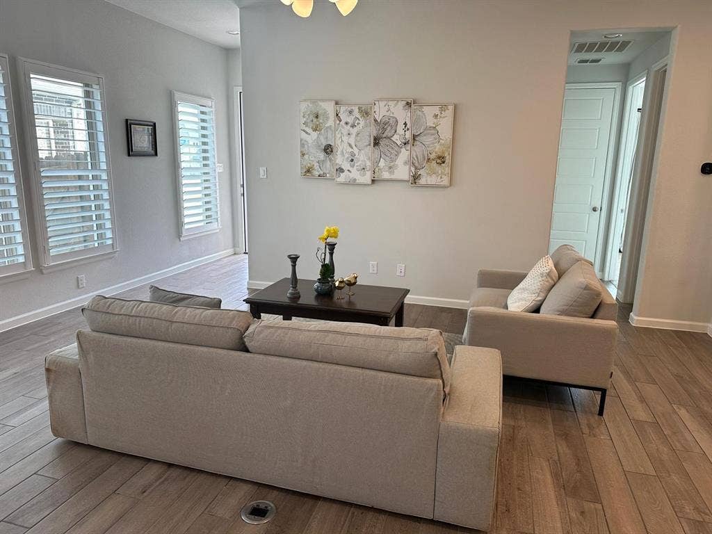 5308 Tupper Avenue, Fate, TX 75087 Wood-finish flooring, white plantation shutters, light gray wall paint, and a built-in ceiling light fixture