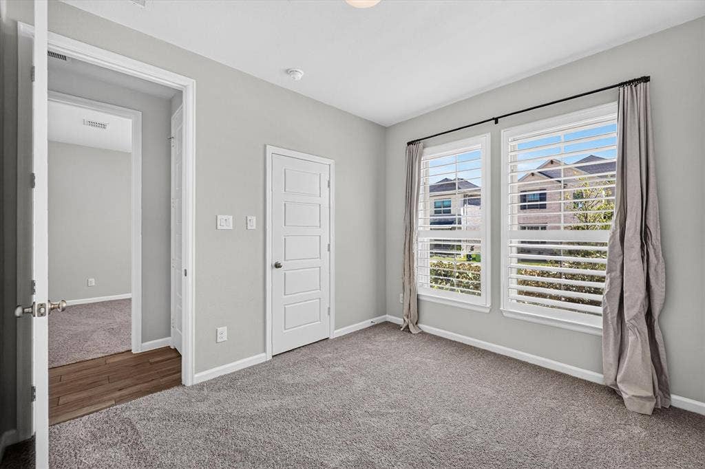 5308 Tupper Avenue, Fate, TX 75087 Dual windows with white plantation shutters, gray carpet flooring, and a contemporary five-panel interior door